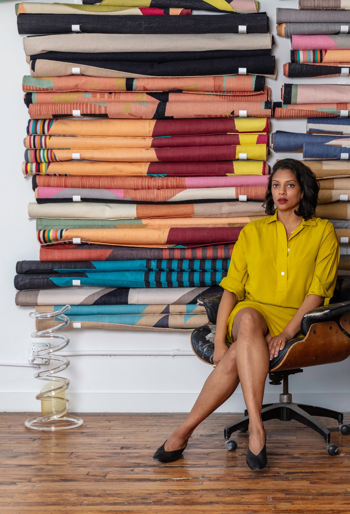 Arati Rao pose devant un mur de tapis tissés et jetés de sa compagnie Tantuvi.